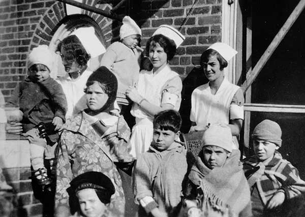 Student nurses and pediatric patients enjoy fresh air and sunshine on the roof of the hospital, c.1925.