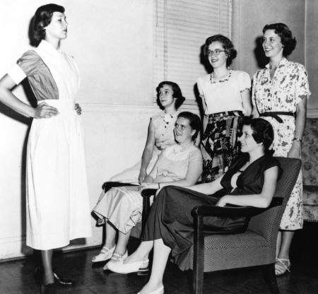 In 1950, Mary Washington College students look over the uniform they will be wearing as members of the school's first BSN class.	Uniform modeled by Frances Jones (later Schwark), BSN 1954. Eleanor Crowder Bjoring Center for Nursing Historical Inquiry, University of Virginia School of Nursing.