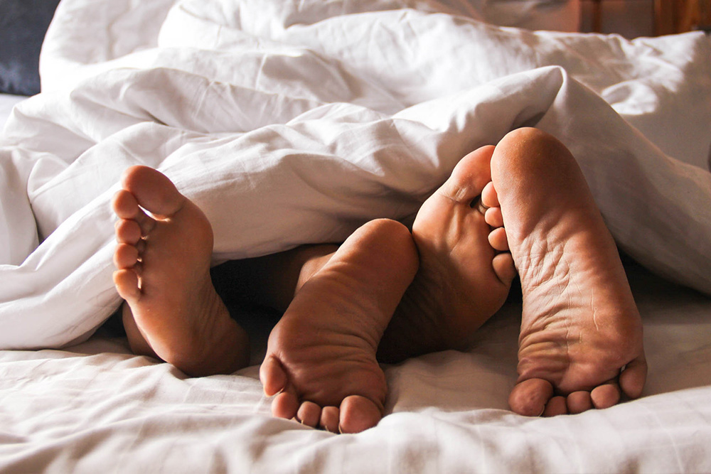 An intimate image of a couple's feet in bed used to illustrate Kim Acquaviva's Hill Foundation Grant funded study of sexual health at end of life.
