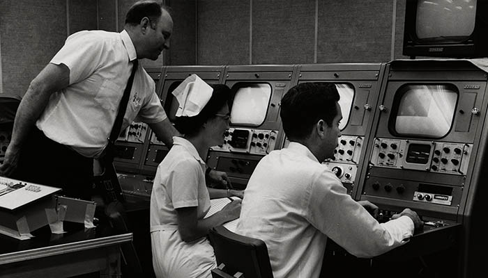 A historic image of a nurse and doctors using a computer