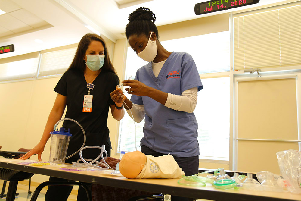 An image of a CNL student learning how to insert a bronchial tube into a pediatric patient.
