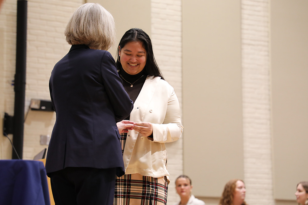 CNL student Michelle Hilado earns a pin from Dean Marianne Baernholdt at the White Coat Ceremony in January 2023.