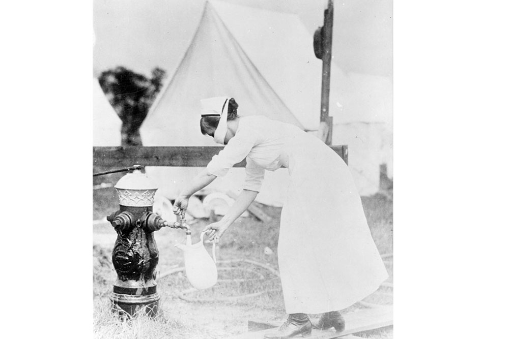 Nurse wearing a mask at water pump 1918