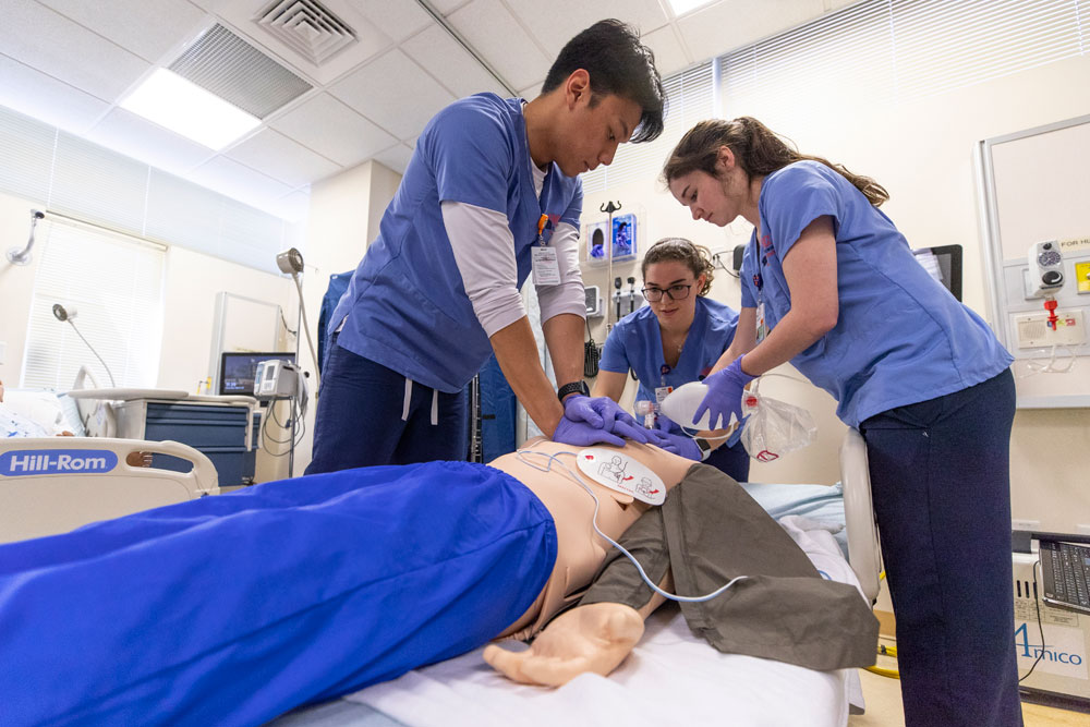 Three UVA Nursing students practice skills with a high-tech mannequin.