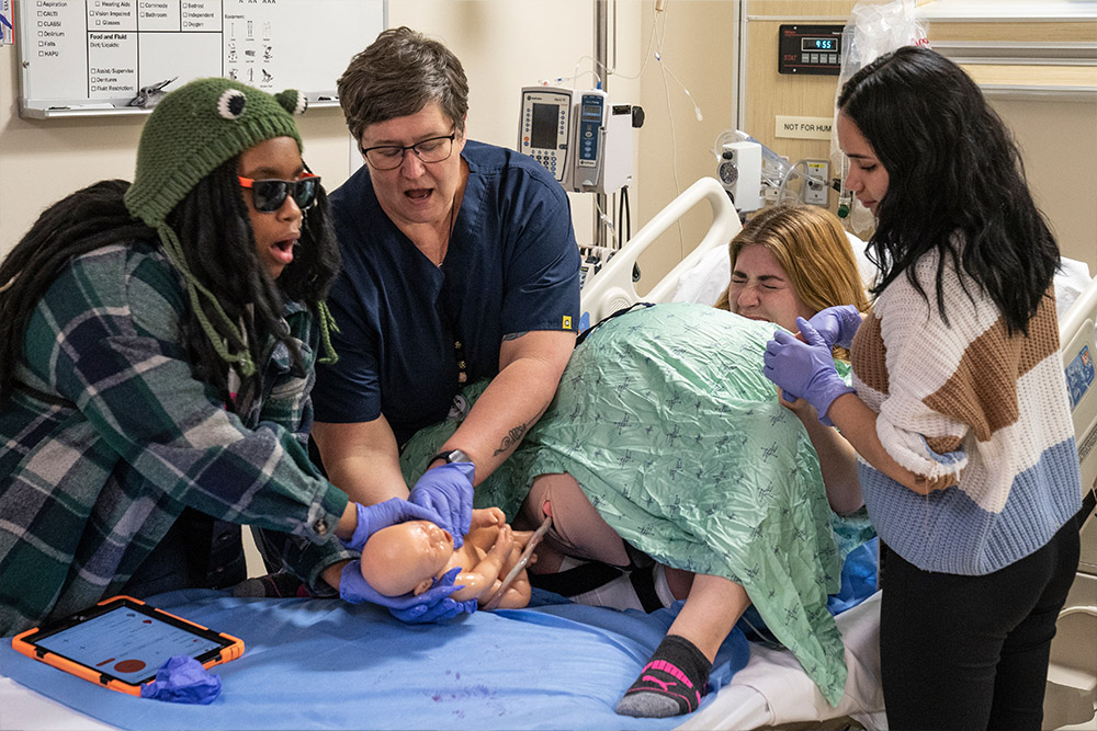 A Starr Hill Pathways student helps tend in a birthing simulation.