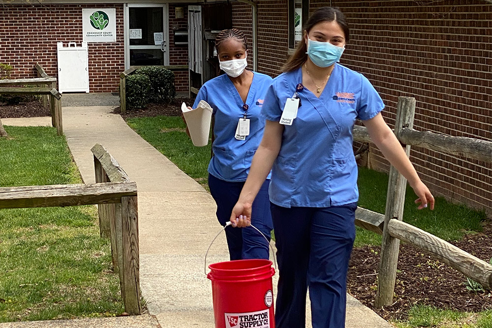 nursing students carry buckets of dirt