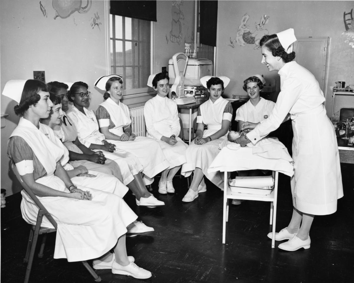 Amelia Lipchak, pediatric clinical supervisor, demonstrates infant feeding to a group of nursing students, affiliates, and LPN students.	Eleanor Crowder Bjoring Center for Nursing Historical Inquiry, University of Virginia School of Nursing.