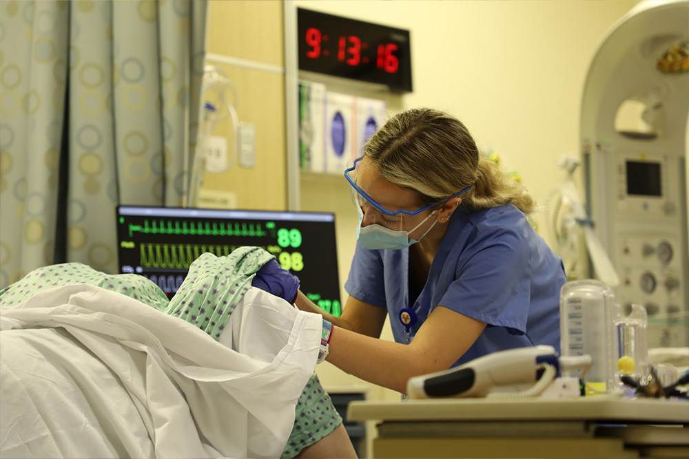 A nursing student checking the dilation of her simulated OB patient.