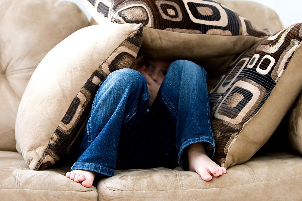 A toddler hiding in the couch cushions