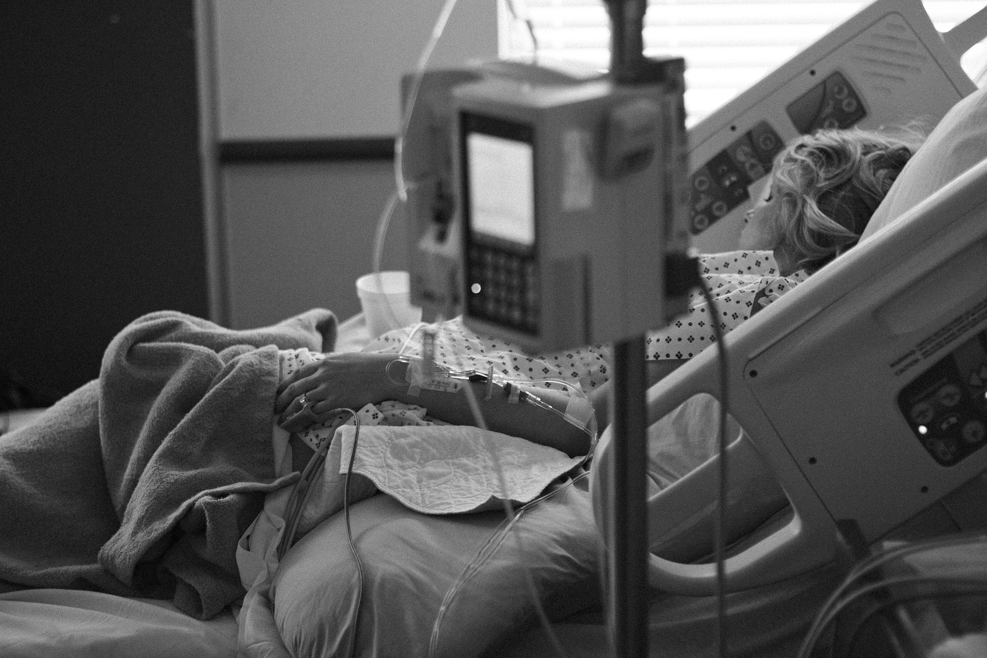 black and white image of a hospital room with a patient in bed- PIXABAY