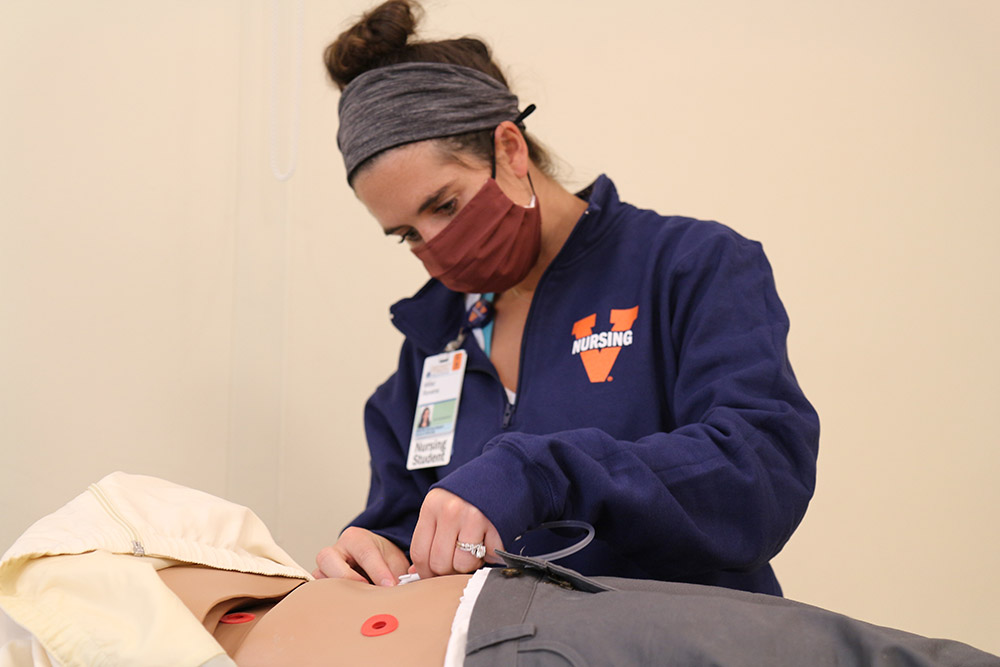 A CNL student practices placing a gastric tube.
