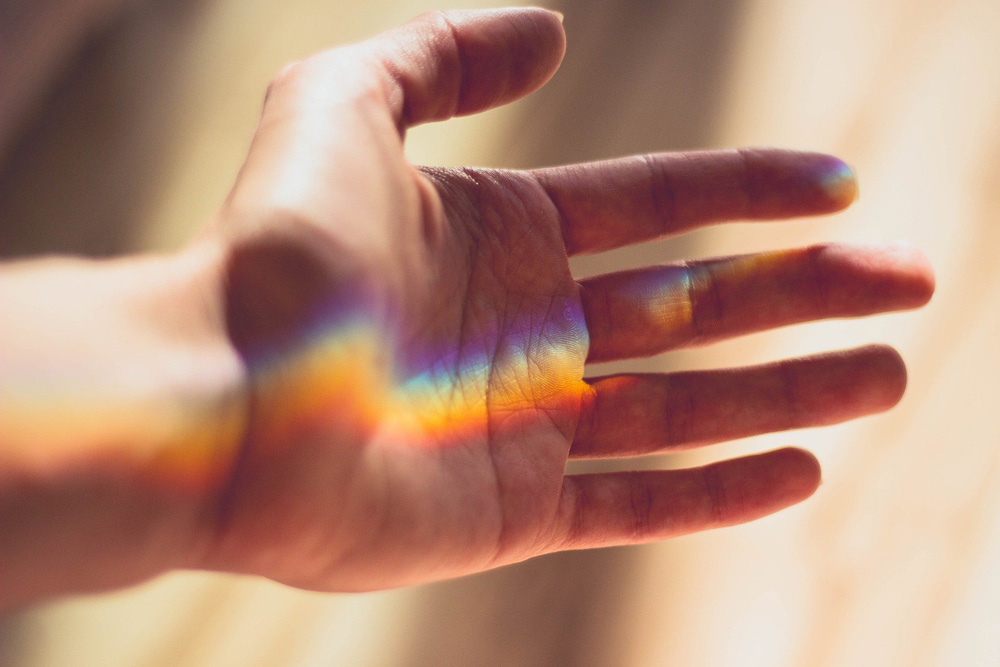 A photo of a hand with a rainbow across the palm