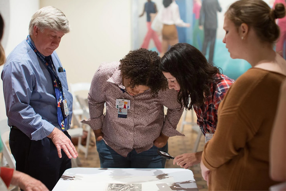 Nursing and medical students at a Heart of Medicine gathering pore over art at the Fralin Museum with docents and curators and museum educators.