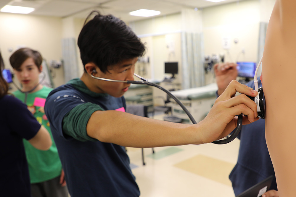 A Starr Hill Pathway middle school student listens to heart sounds through a stethoscope.