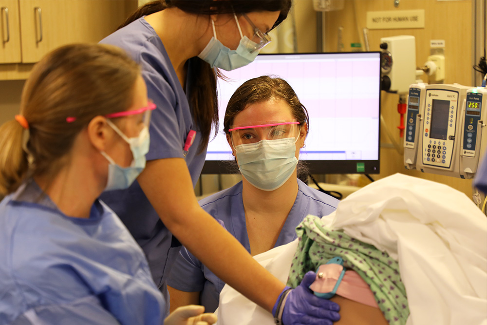 Nursing students and their prof tend a laboring standardized patient mom, part of a new OB simulation.