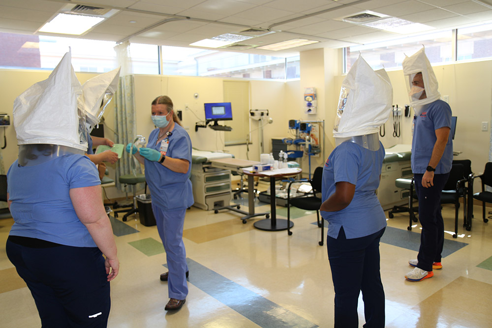 Four CNL students learn about and get fitted for full-head coverings and masks.