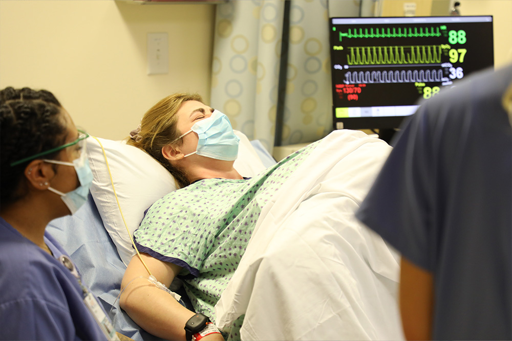 A simulated birthing mother pushes hard during an OB simulation.