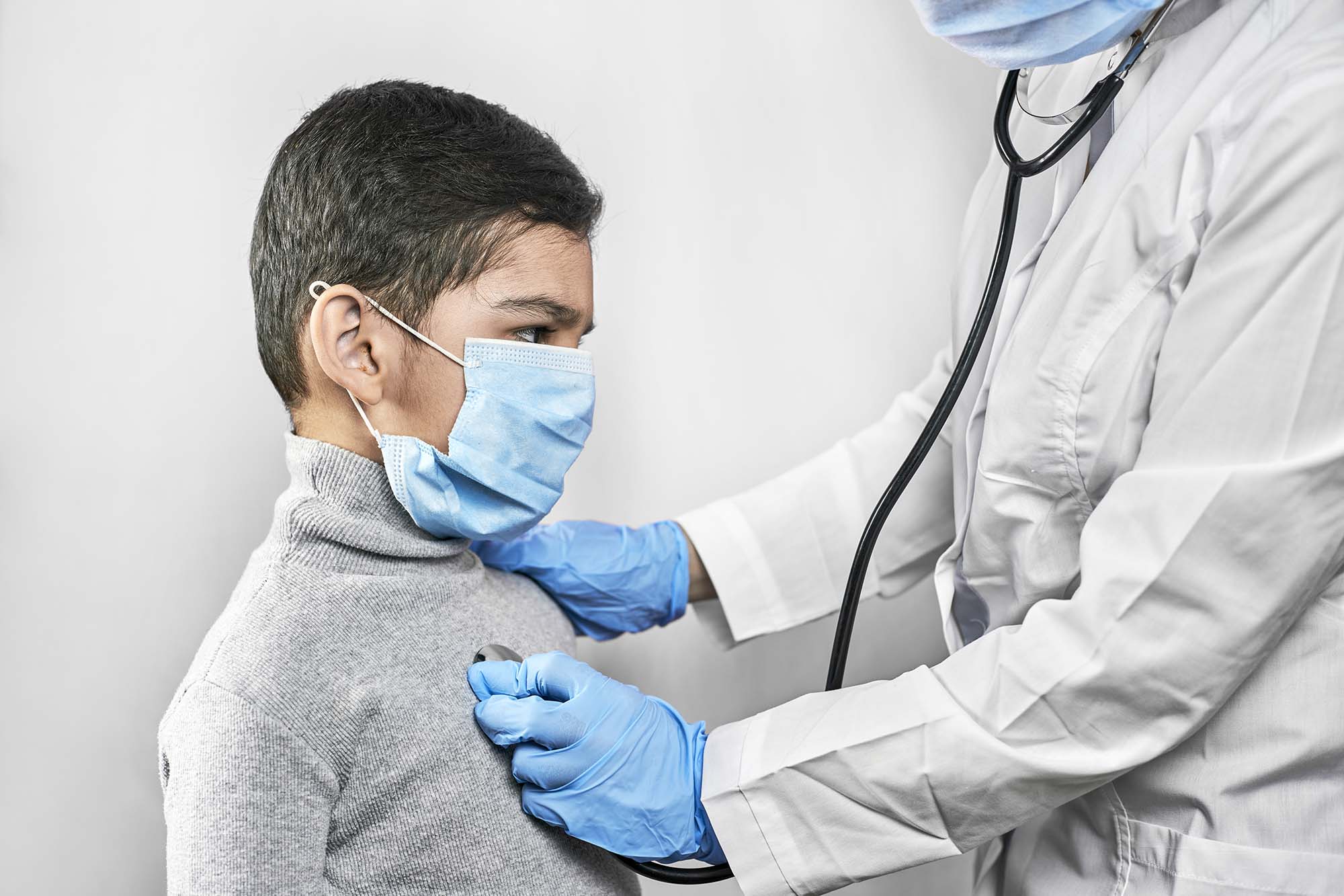 An image of a masked student being cared for by a school nurse.