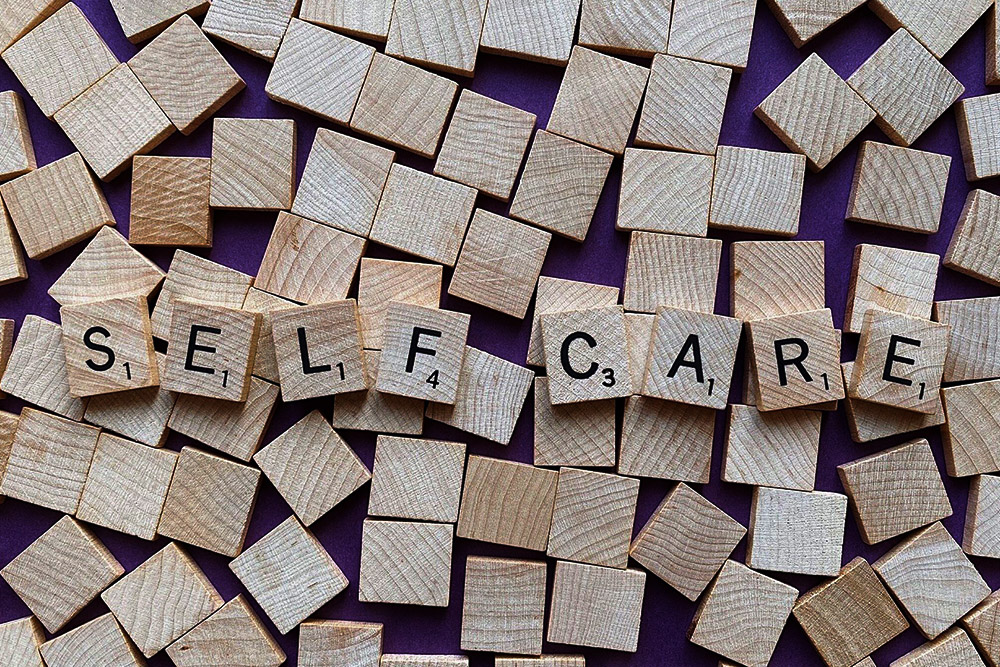 An image of Scrabble pieces spelling out the words self care, referencing the programming of the Compassionate Care Initiative