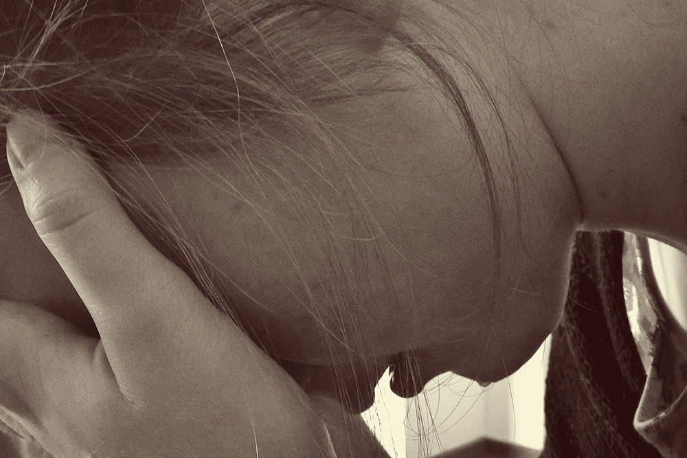 An image of a stressed out woman with her head in her hands.