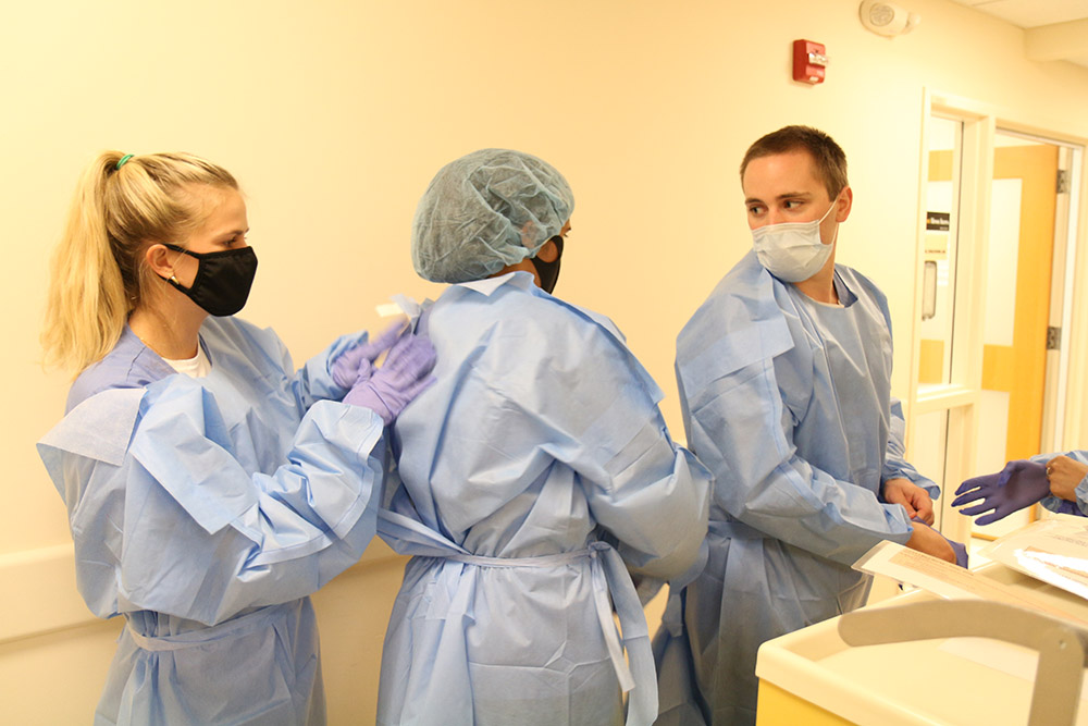 A quartet of CNL students practice suiting up in PPE in the sim lab.